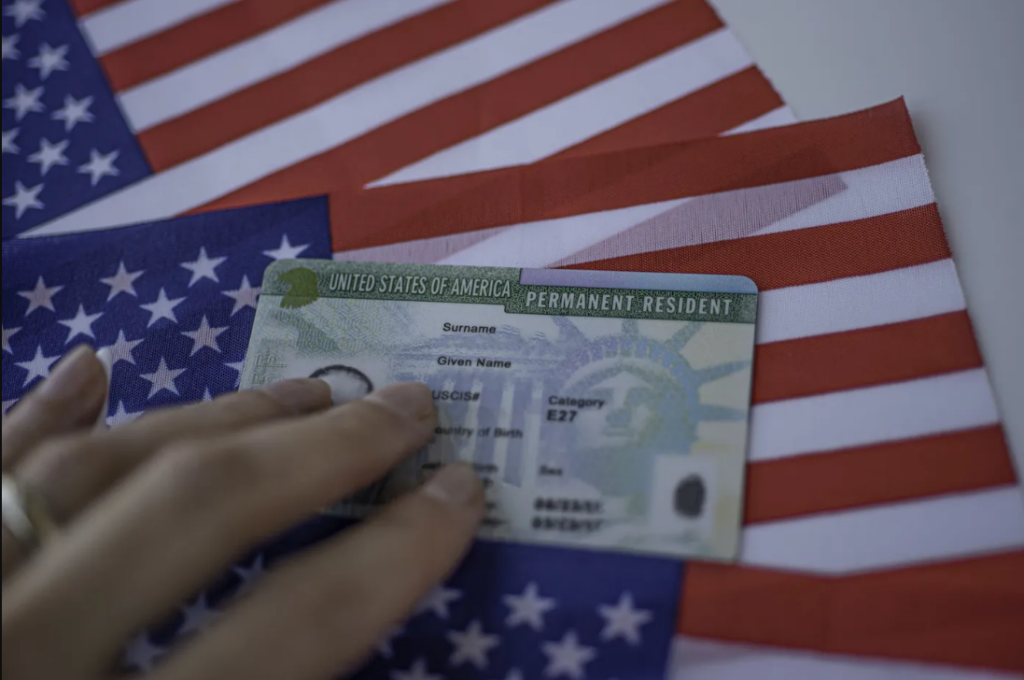 A green card ion top of US flag