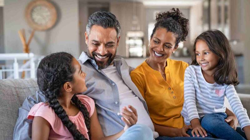 Happy family sitting in sofa while looking at each other and laughing