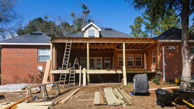 A house being renovated with stacks of wood in front of it