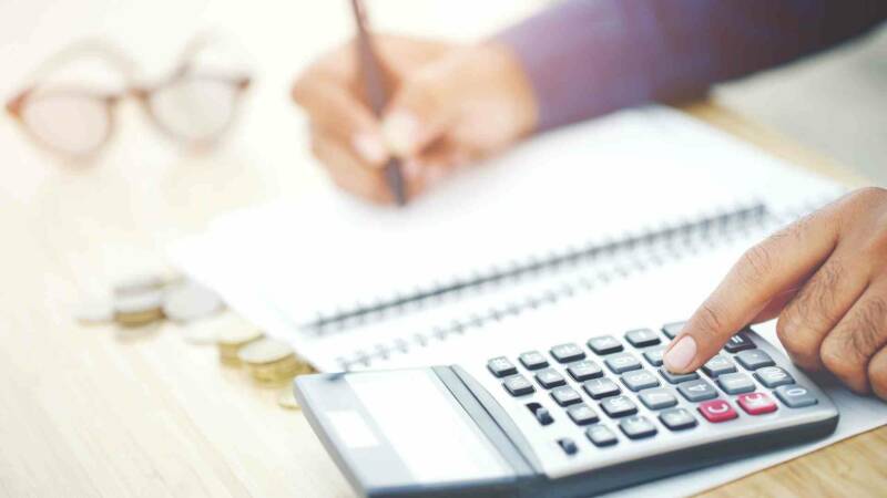 An e2 visa foreign investor calculating his budget in a calculator while writing it down in a book