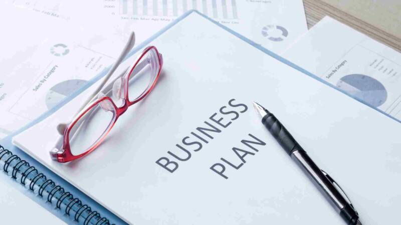 Business plan proposal for e2 investor visa with a pen and red glasses above it