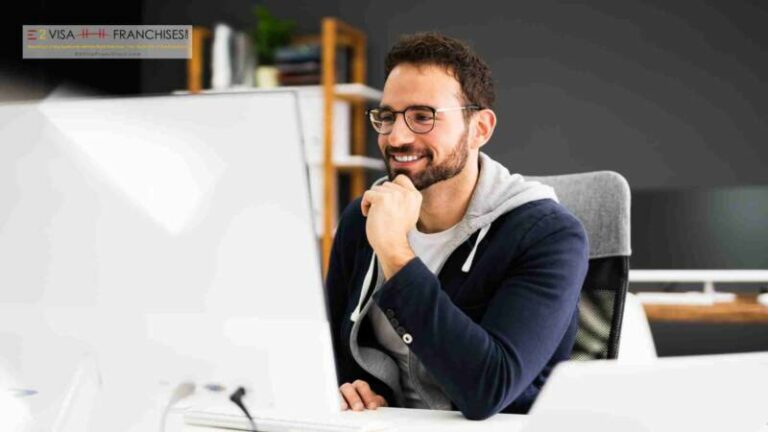 E2 business visa entreprenuer is looking at his computer while smiling