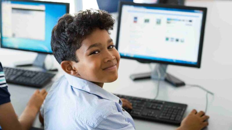 A kid smiling at the camera while at school