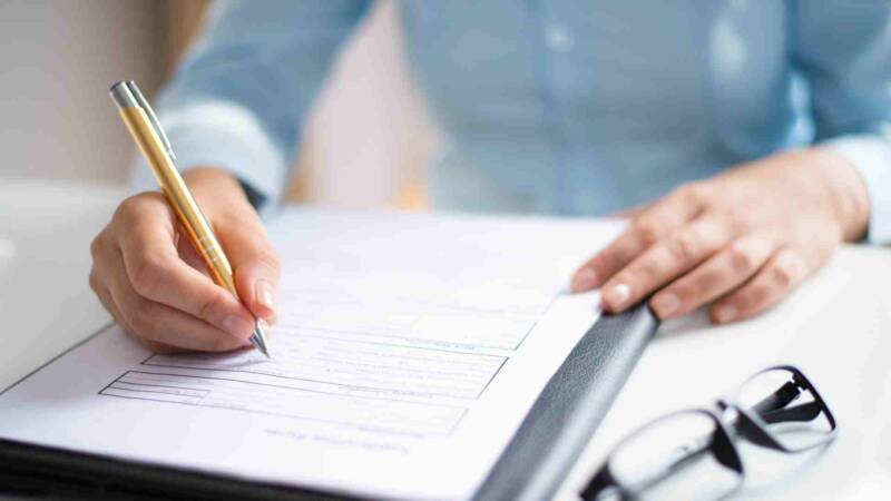 A woman writing for an E2 visa applications to avoid E2 visa denials