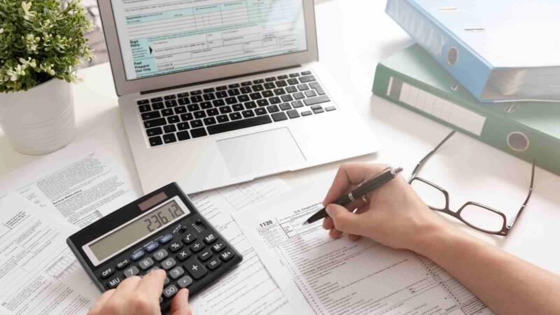 An investor filing for tax with calculator and laptop