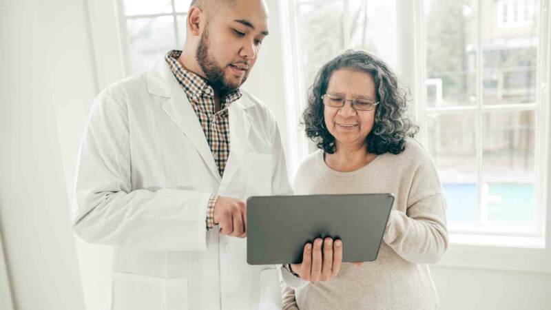 A doctor is discussing a test result in a tablet with a patient