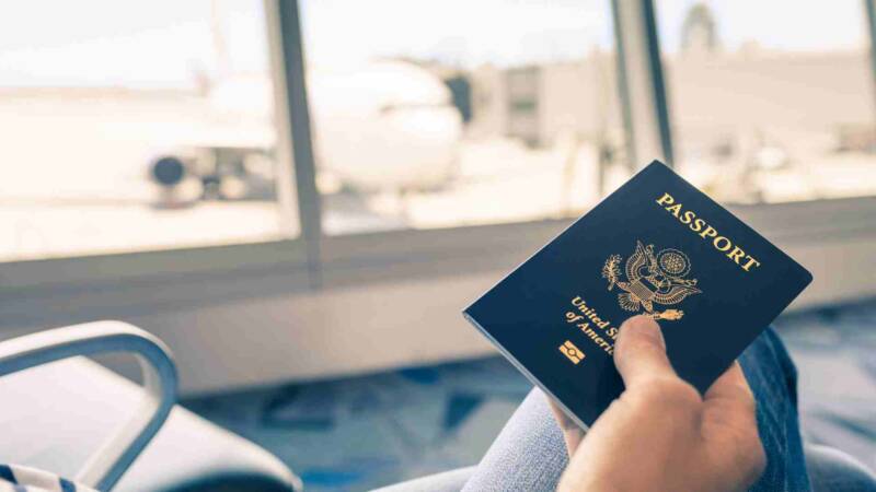 A green card holder holding a US passport in the airport