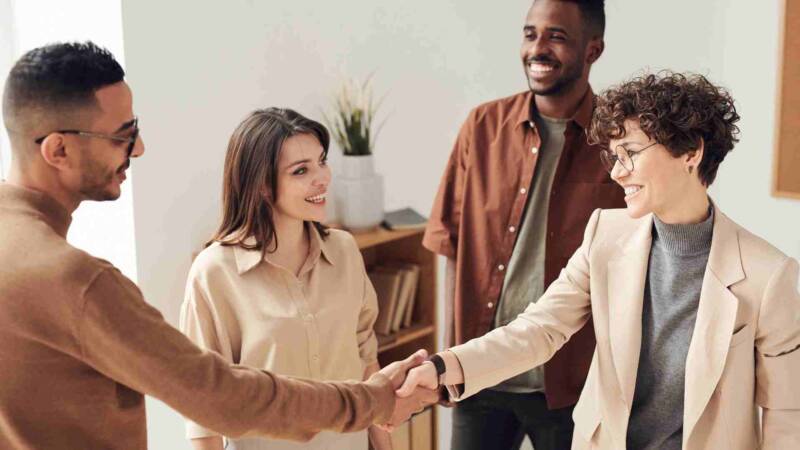 A franchisor and franchisee shaking hand with 2 team members