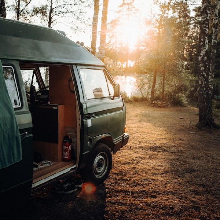 Camper van parked in woods looking at sun set